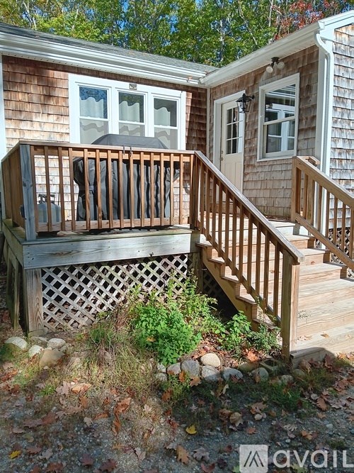 A wooden deck with a lattice patterned bench and a staircase leading to a house.
