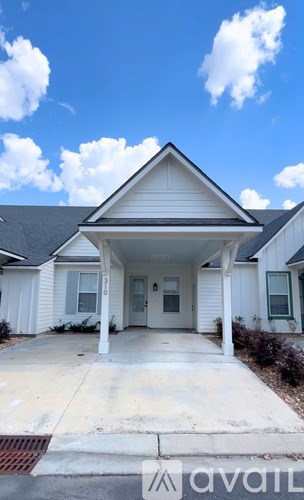 A white house with a black roof and a porch.