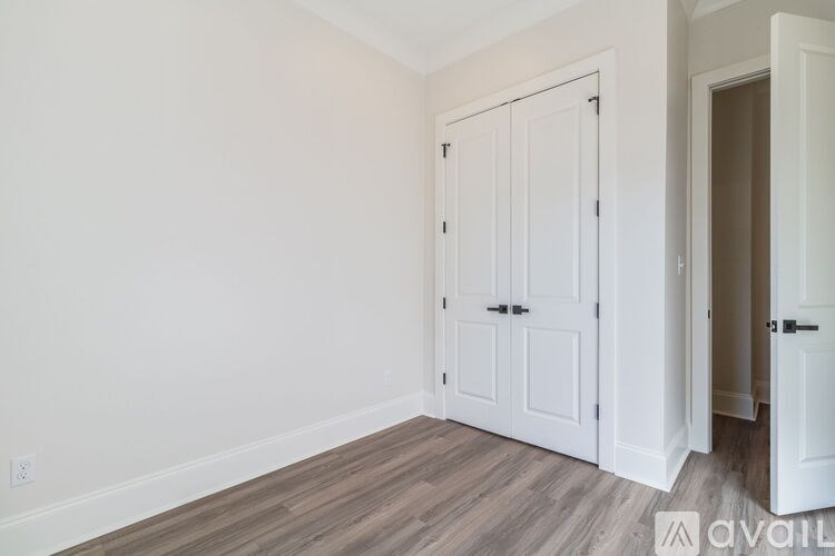 A room with a white door and a wooden floor.