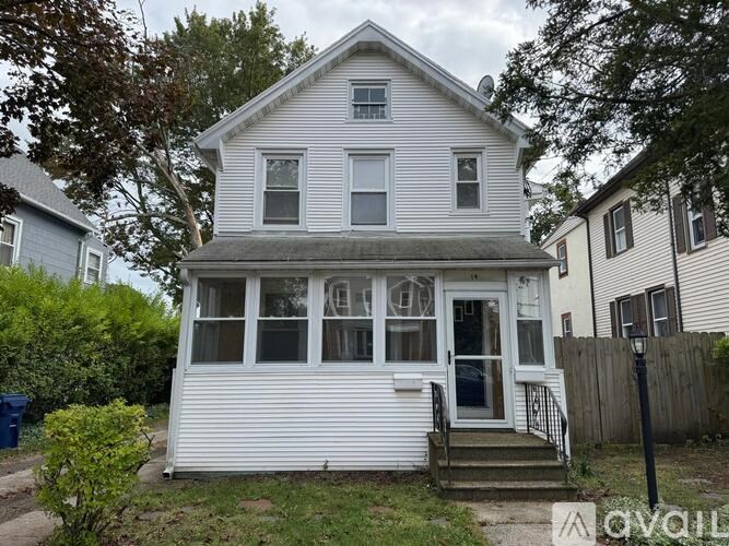 A white house with a grey roof and a small porch.
