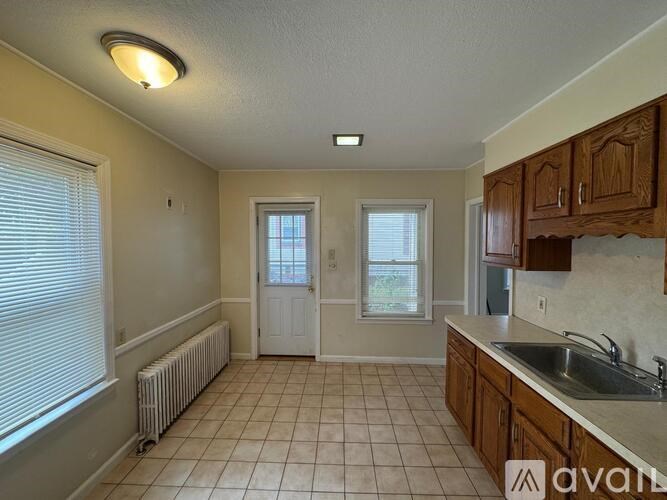 A kitchen with a white door and a window with blinds.