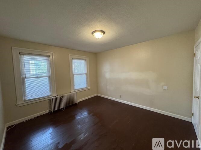 A room with wooden floors and two windows.