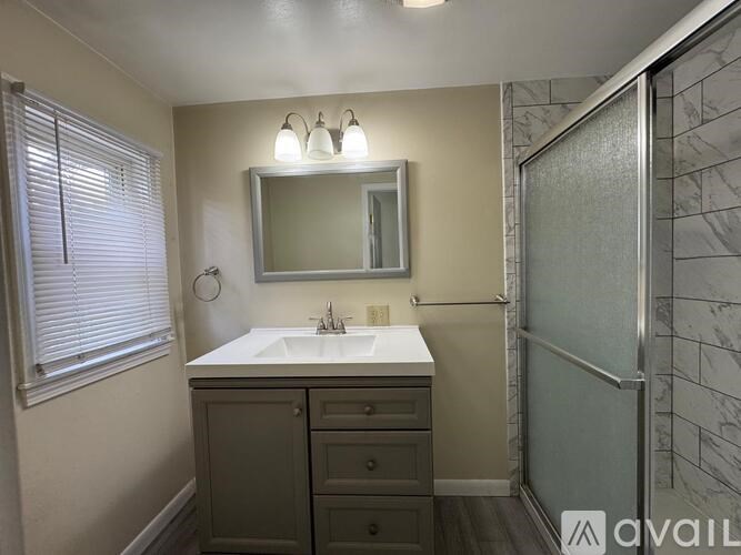 A bathroom with a sink, mirror, and shower.