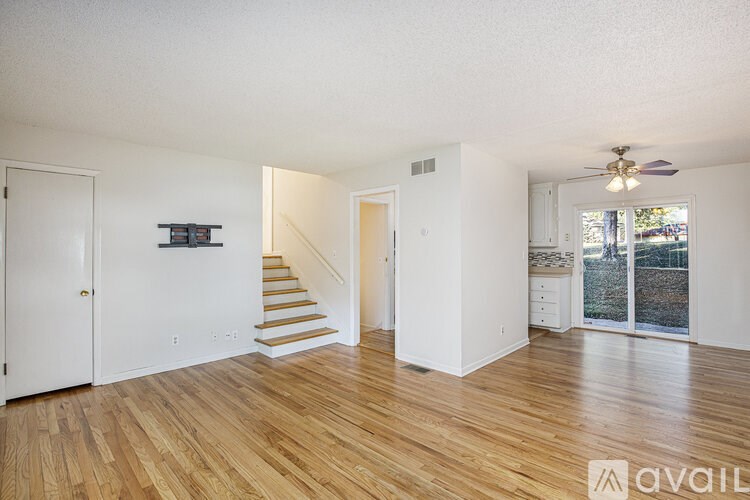 A spacious living room with wooden floors and white walls.
