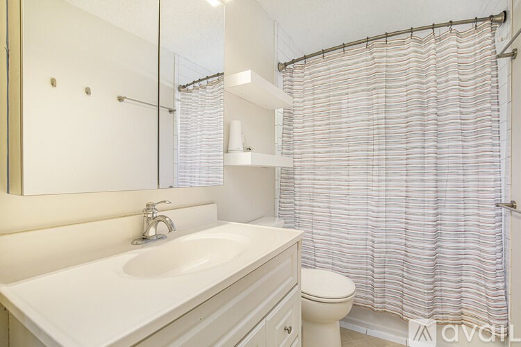 A white bathroom with a sink, toilet, and shower curtain.