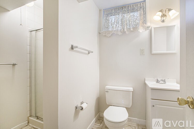 A white bathroom with a toilet, sink, and shower.