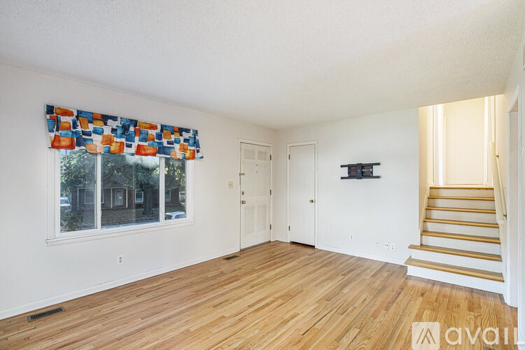 A room with wooden floors and a staircase leading to another room.