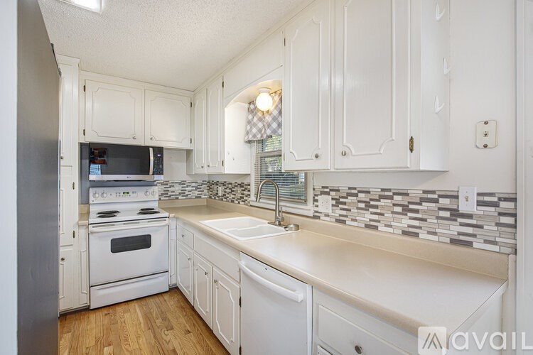 A kitchen with white cabinets and a checkered backsplash.
