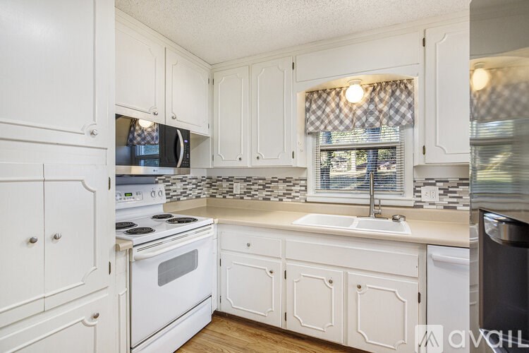 A kitchen with white cabinets and a checkered backsplash.