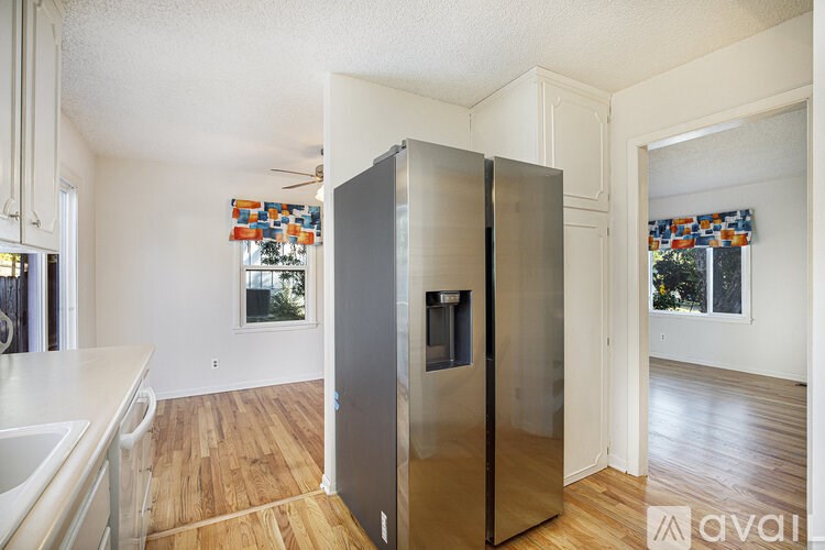 A kitchen with a refrigerator, sink, and wooden floors.