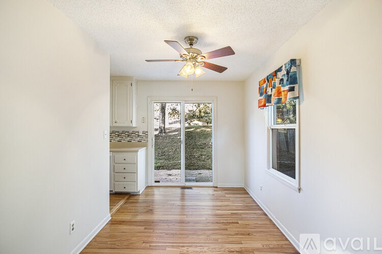 A room with a ceiling fan and a window overlooking a backyard.