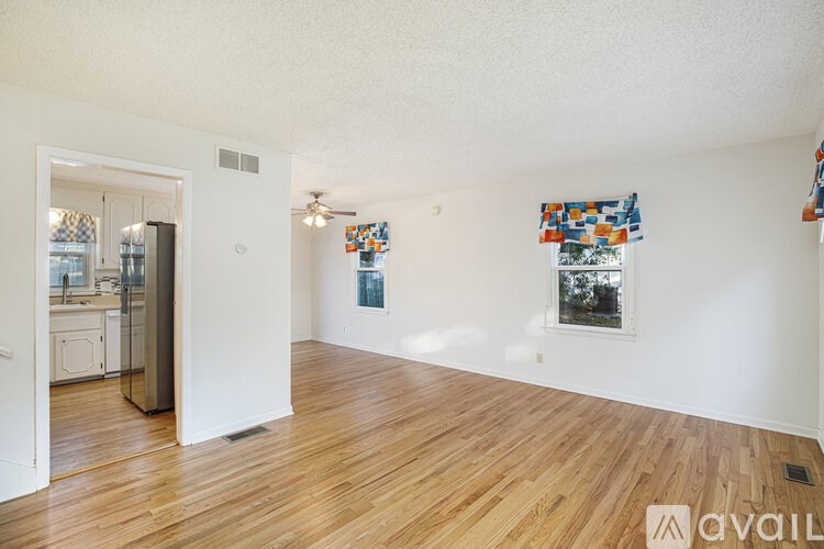 A room with wooden floors and a window with a view of trees.