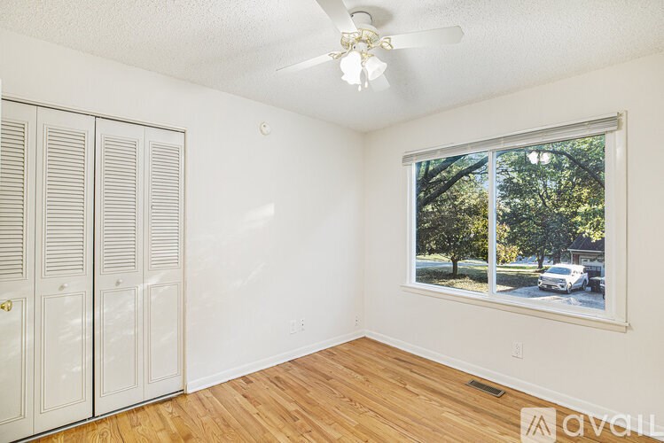 A room with a window showing trees and a car outside.
