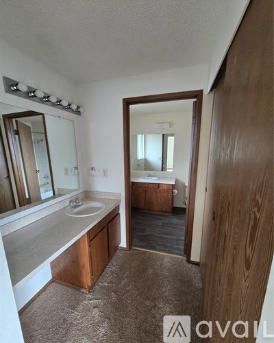 A bathroom with a sink, mirror, and wooden cabinet.