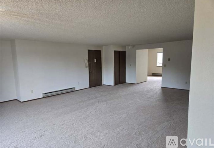 A spacious room with a carpeted floor and a door on the left side.
