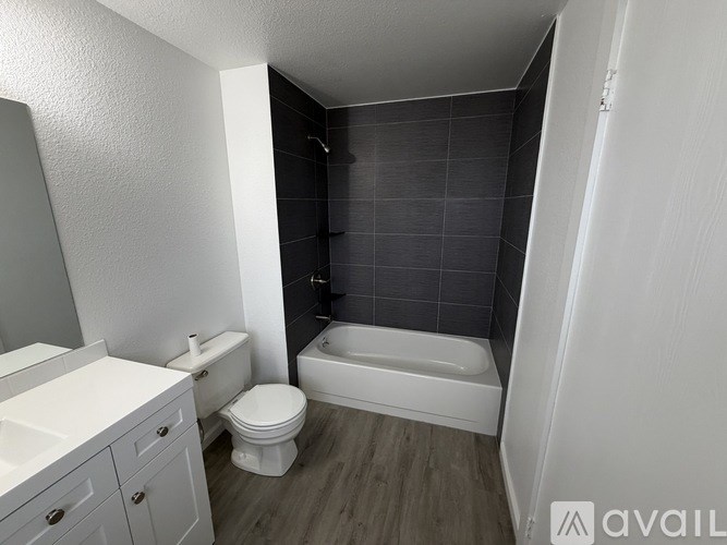 A spacious empty room with a carpeted floor and a white refrigerator in the corner.