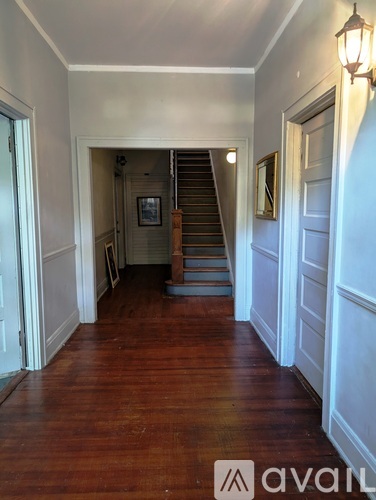 A hallway with wood floors and white walls.