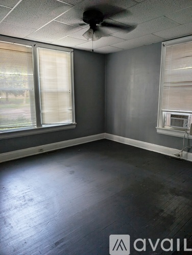 A room with a fan on the ceiling and a window with blinds.