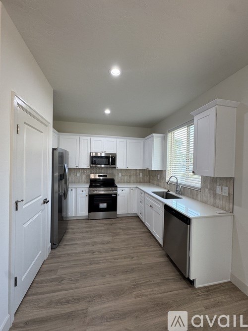 A kitchen with white cabinets and a wooden floor.
