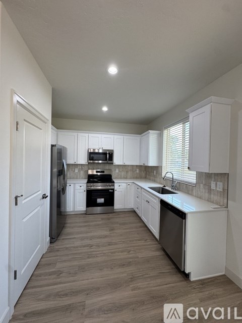 A kitchen with white cabinets and a wooden floor.