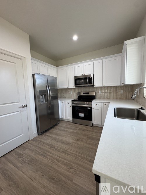 A kitchen with white cabinets and a wooden floor.