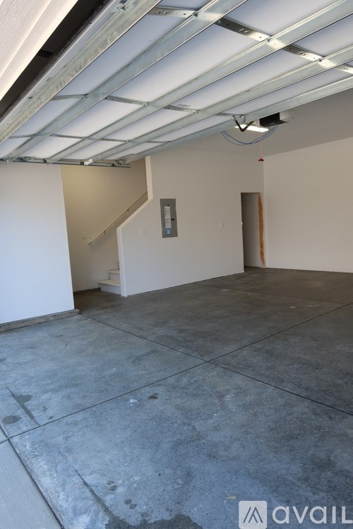 A spacious room with a concrete floor and a staircase leading to another level.