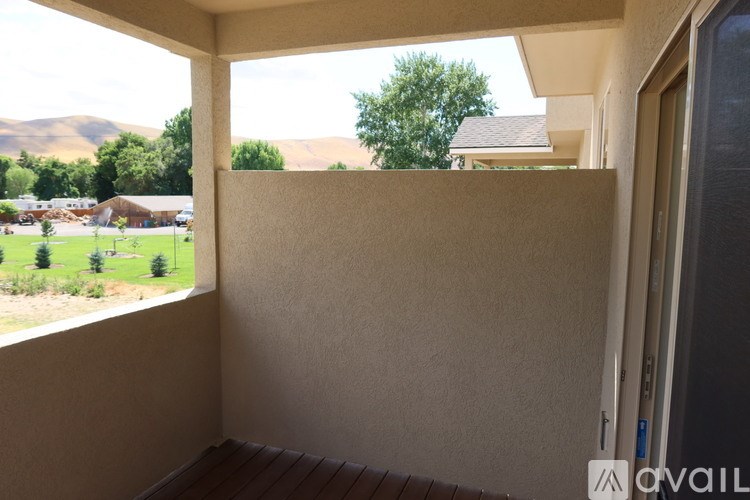 A balcony with a view of a green landscape and houses.