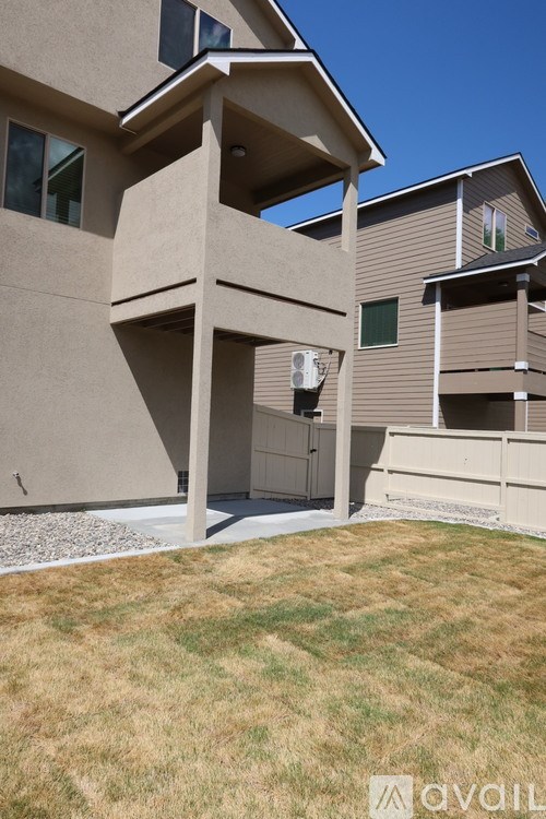 A modern house with a beige exterior and a large front yard.