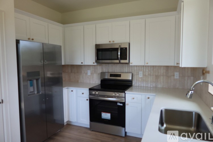 A kitchen with white cabinets and a stainless steel refrigerator.