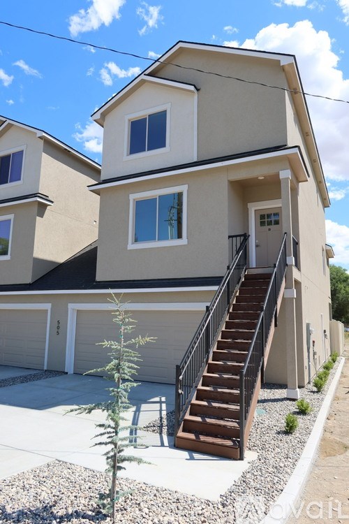 A two-story house with a garage and a small tree in front.