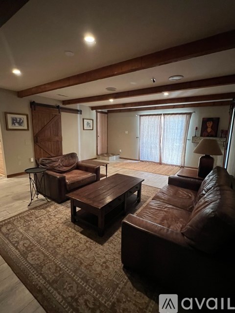 A living room with brown leather furniture and a rug.