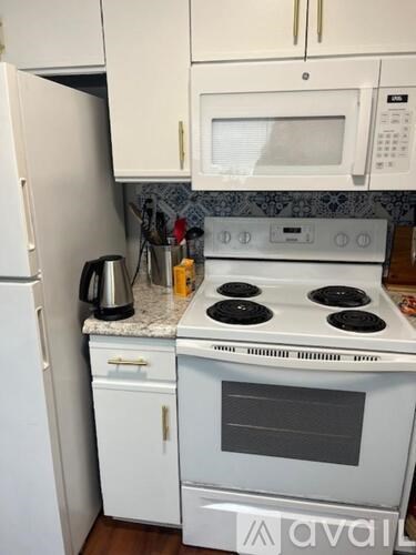 A white kitchen with a stove top oven and a microwave above it.