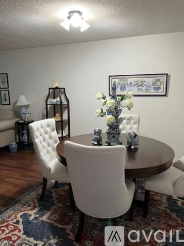 A dining room with a round table and white chairs.