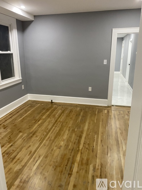 A room with wooden flooring and a grey wall.