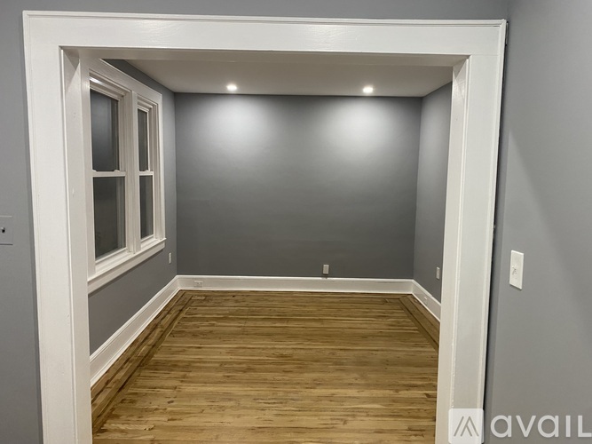 A room with wooden flooring and a white door frame.