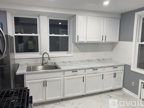 A kitchen with white cabinets and a marble countertop.