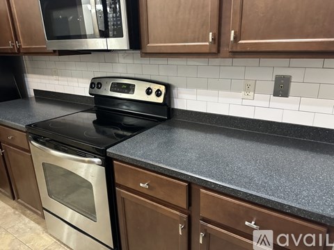 A kitchen with a black stove top oven and a black counter top.