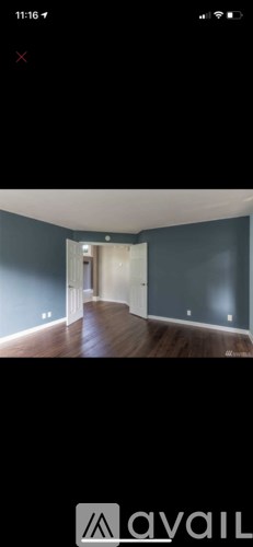 A room with wooden flooring and a doorway leading to another room.
