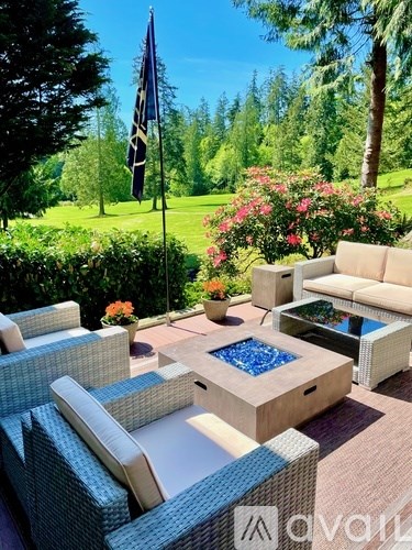 A patio with a blue chair and a table with a glass top.