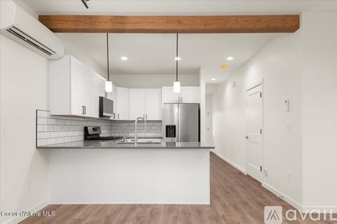 A modern kitchen with white cabinets and a wooden beam ceiling.