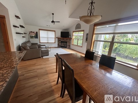 A living room with a wooden table and chairs, a couch, a television, and a fireplace.