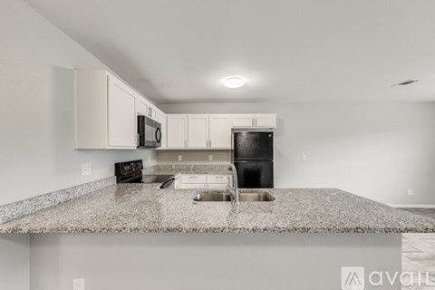 A kitchen with granite countertops and white cabinets.