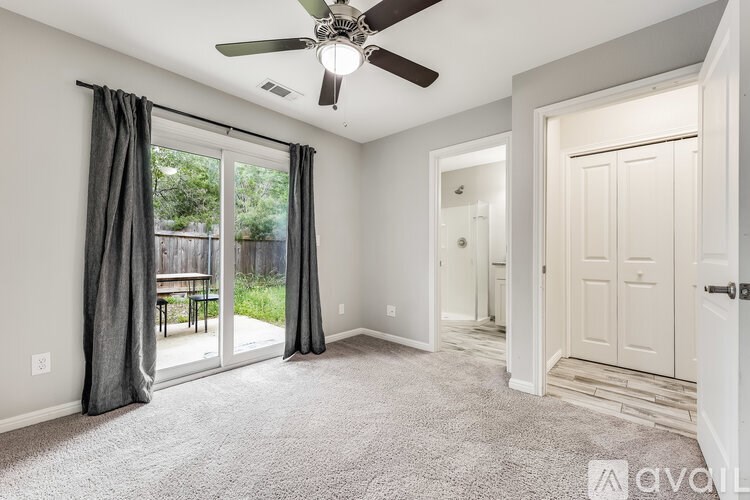 A room with a ceiling fan and sliding glass doors.