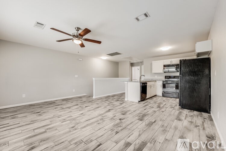 A spacious room with a ceiling fan and wooden flooring.