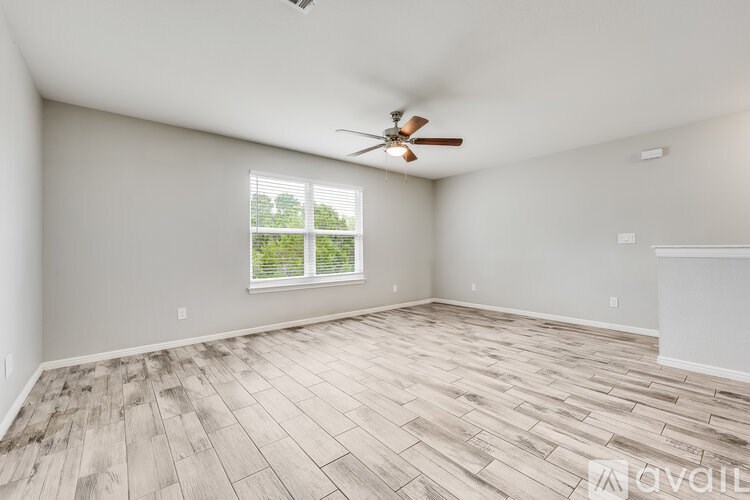 A room with a ceiling fan and wooden flooring.