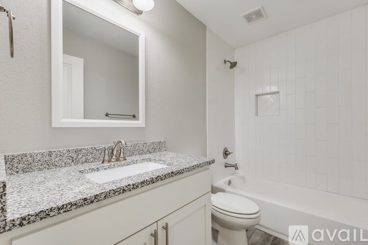 A bathroom with a granite countertop and white fixtures.