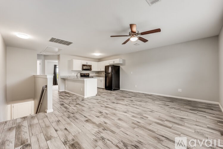 A spacious living room with a ceiling fan and hardwood flooring.