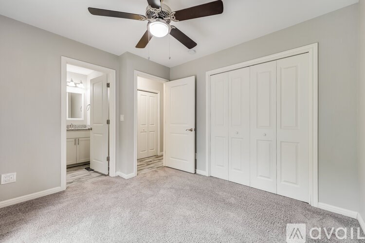 A room with a ceiling fan and three doors.