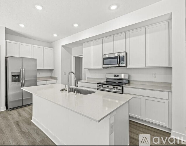 A modern kitchen with white cabinets and stainless steel appliances.