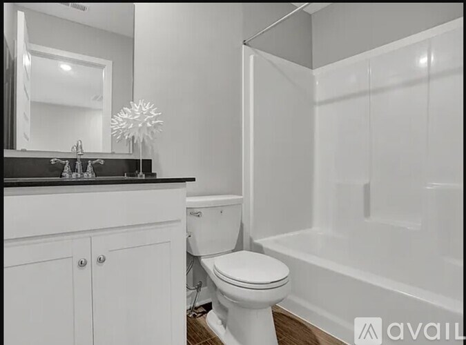 A white toilet is in a bathroom with a white tub.